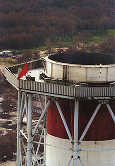 Victoire ! Une banderole apposée sur le réacteur éventré proclame que "le peuple soviétique est plus fort que l'atome" tandis qu'un drapeau rouge est fixé au sommet de la tour d'aération de la centrale à l'issue des travaux de déblaiement. [Tass]
